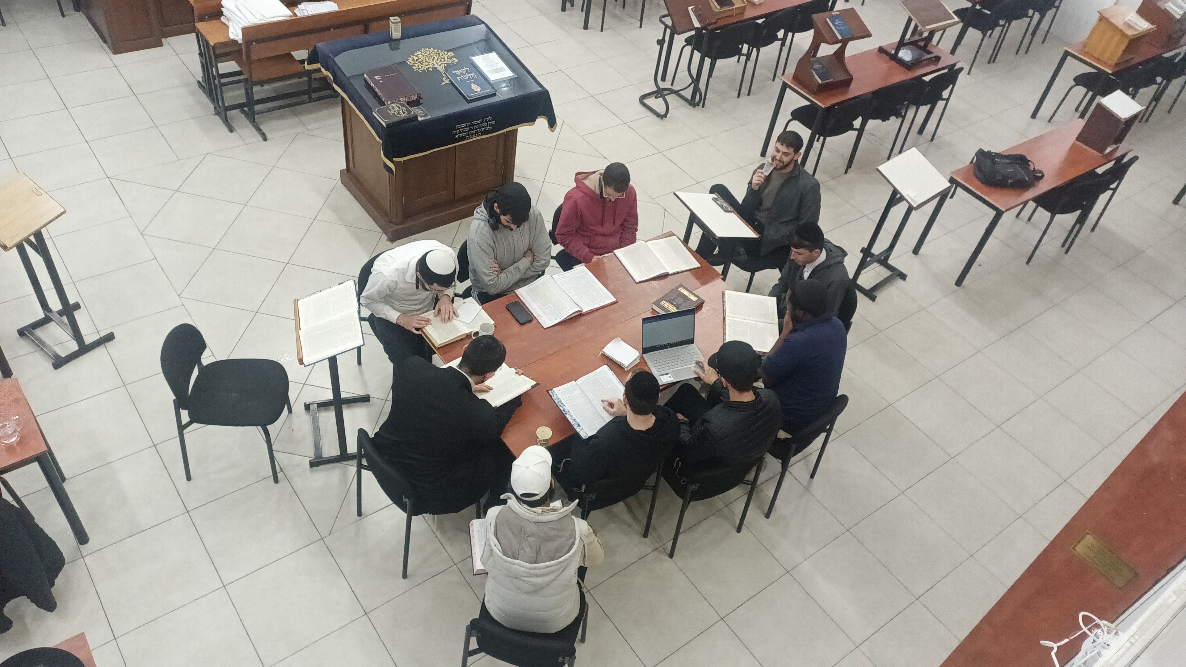 The Breslov Yeshiva talmidim learning together around a table in the beis midrash